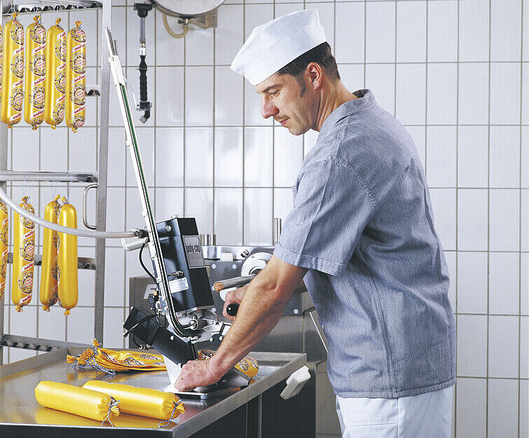 Butcher working with manual clipping machine