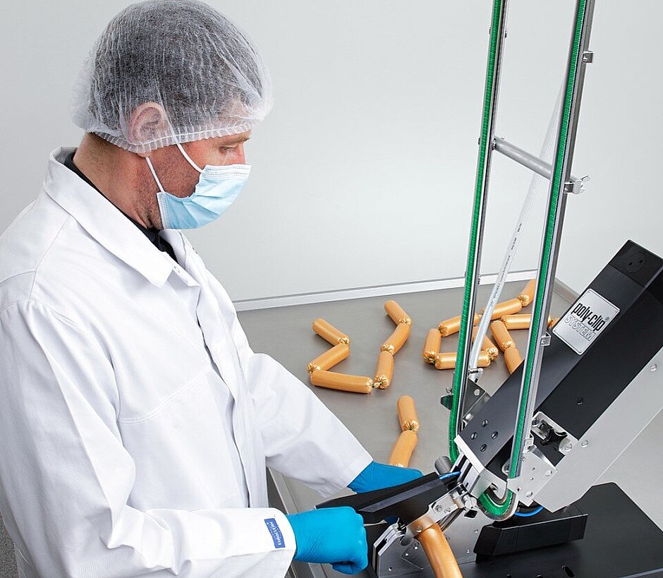 Butcher working with semi-automatic clipping machine